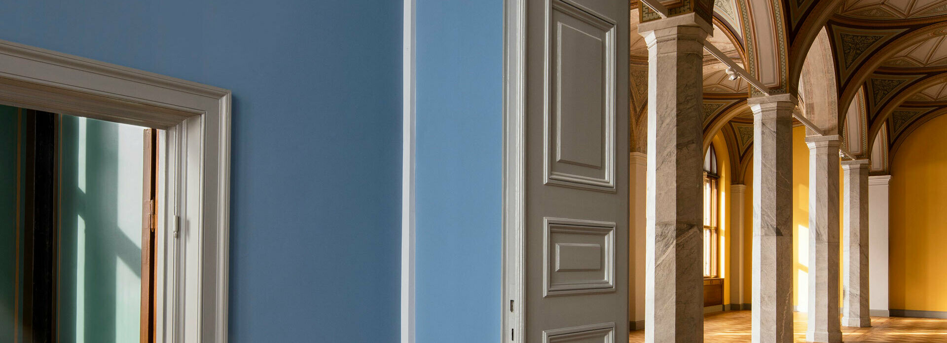 Utblick mot tomma museisalar genom ett par dörröppningar. I den ena salen skymtar dekorativt bemålade valv.