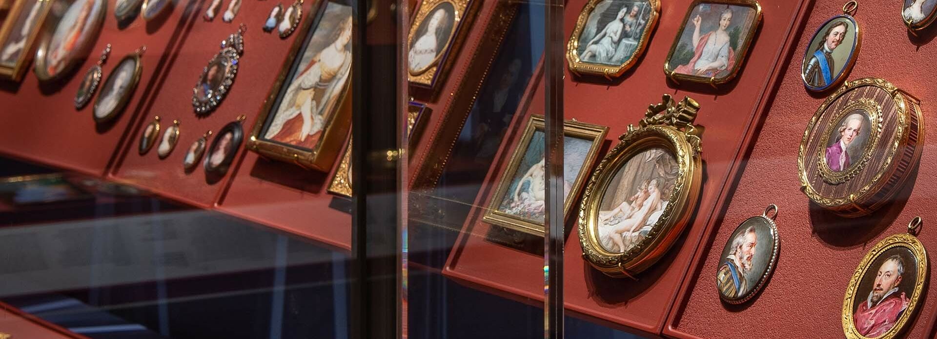 En samling små porträttminiatyrer i en monter.