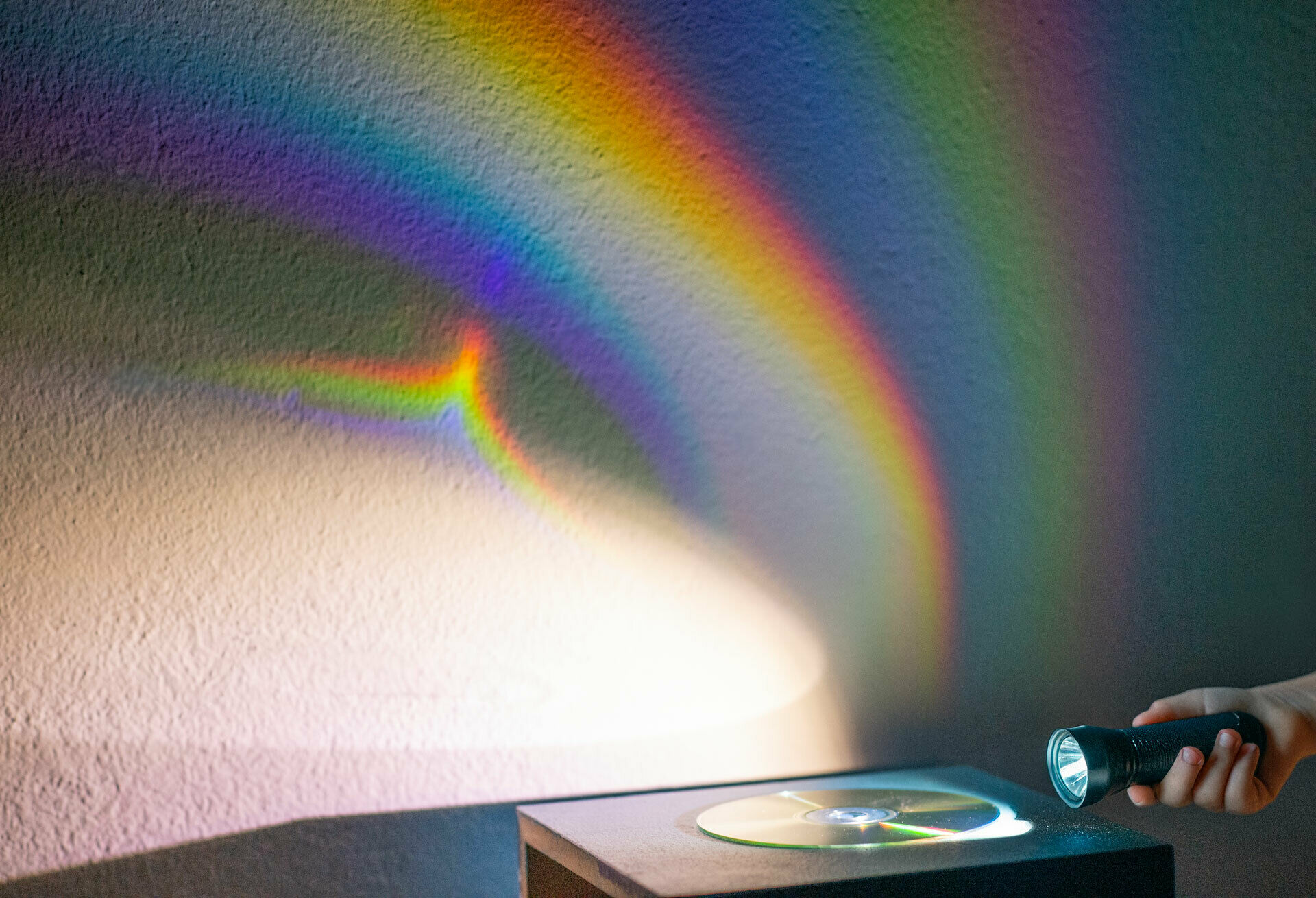 Färgspektrum som uppstår på vit vägg då man lyser med ficklampa på en cd-skiva.