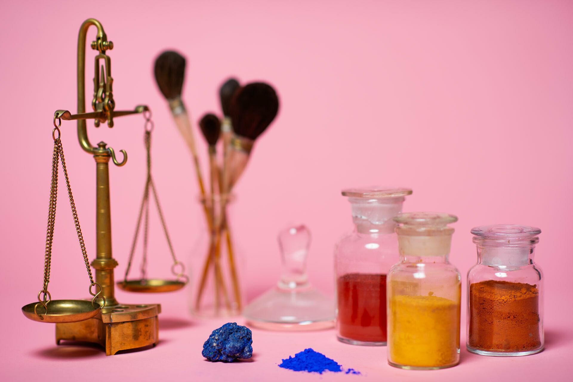 Färgpigment i glasflaskor, penslar och en våg för att väga pigmenten.