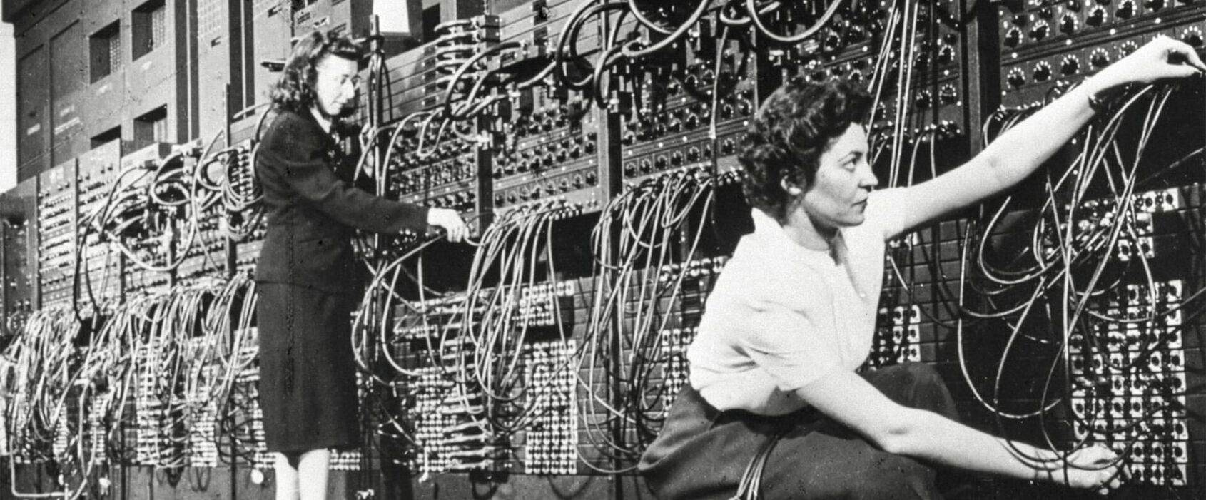 Fotografi från 1946 föreställande två kvinnor som kopplar kablar i en gigantisk dator,