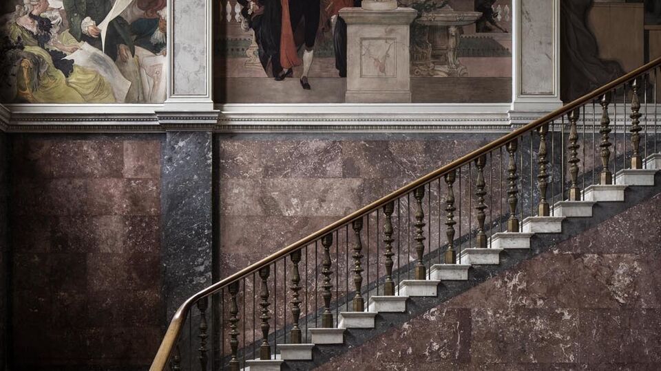 Foto som visar Nationalmuseums trapphall. Trappan upp och Carl Larssons väggmålningar syns i bild.