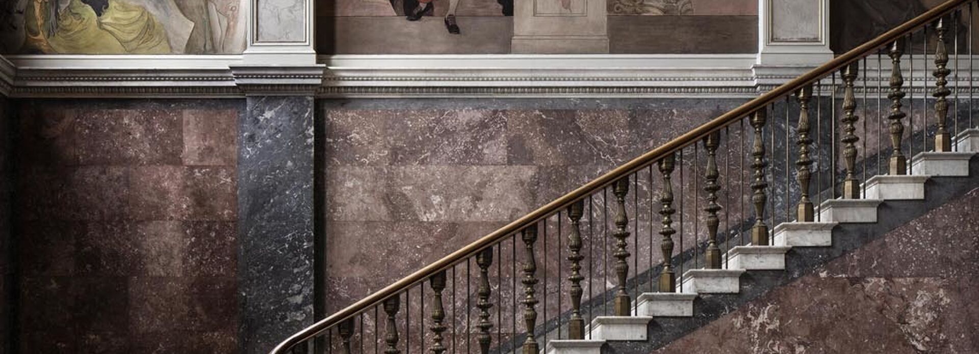 Foto som visar Nationalmuseums trapphall. Trappan upp och Carl Larssons väggmålningar syns i bild.