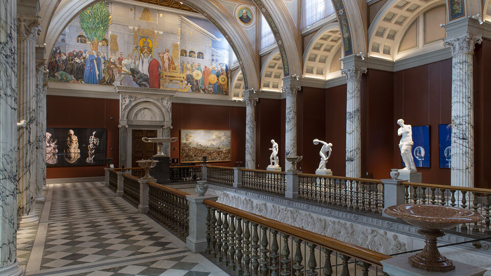 Storslagen trapphall med pelare, väggmålningar och skulpturer.