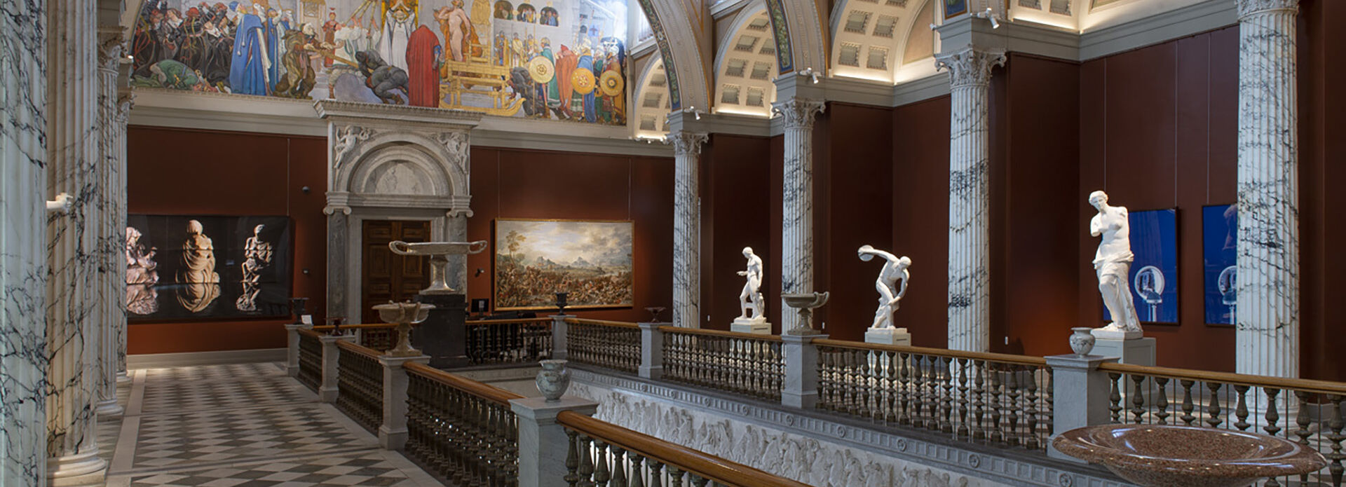 Storslagen trapphall med pelare, väggmålningar och skulpturer.