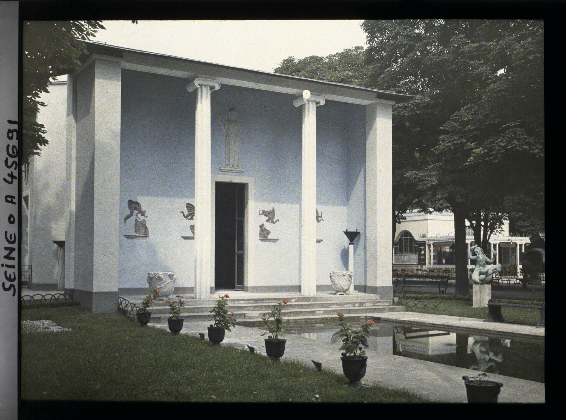 Äldre foto som visar en stram byggnad i nyklassisk stil. I förgrunden en damm och urnor med växter. Sveriges paviljong på Parisutställningen 1925.
