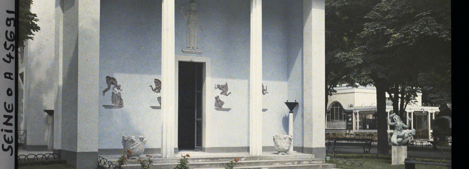 Äldre foto som visar en stram byggnad i nyklassisk stil. I förgrunden en damm och urnor med växter. Sveriges paviljong på Parisutställningen 1925.