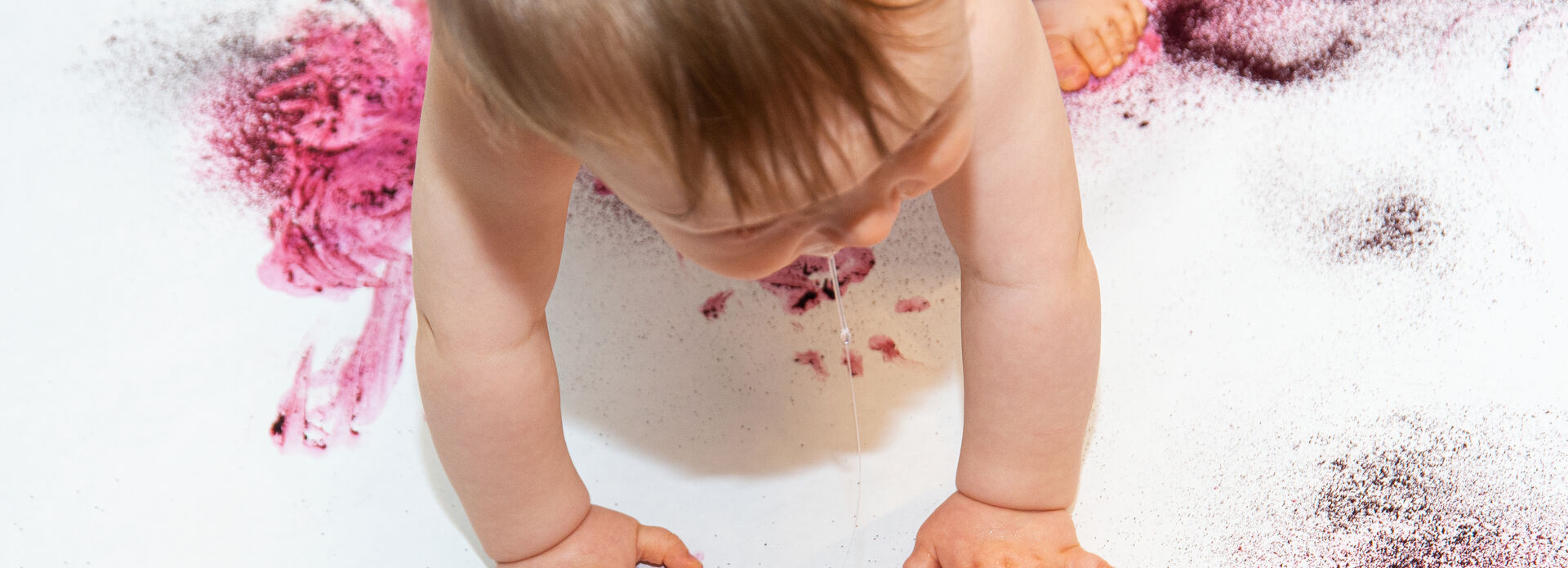 Baby krypande på vitt underlag med färgstänk