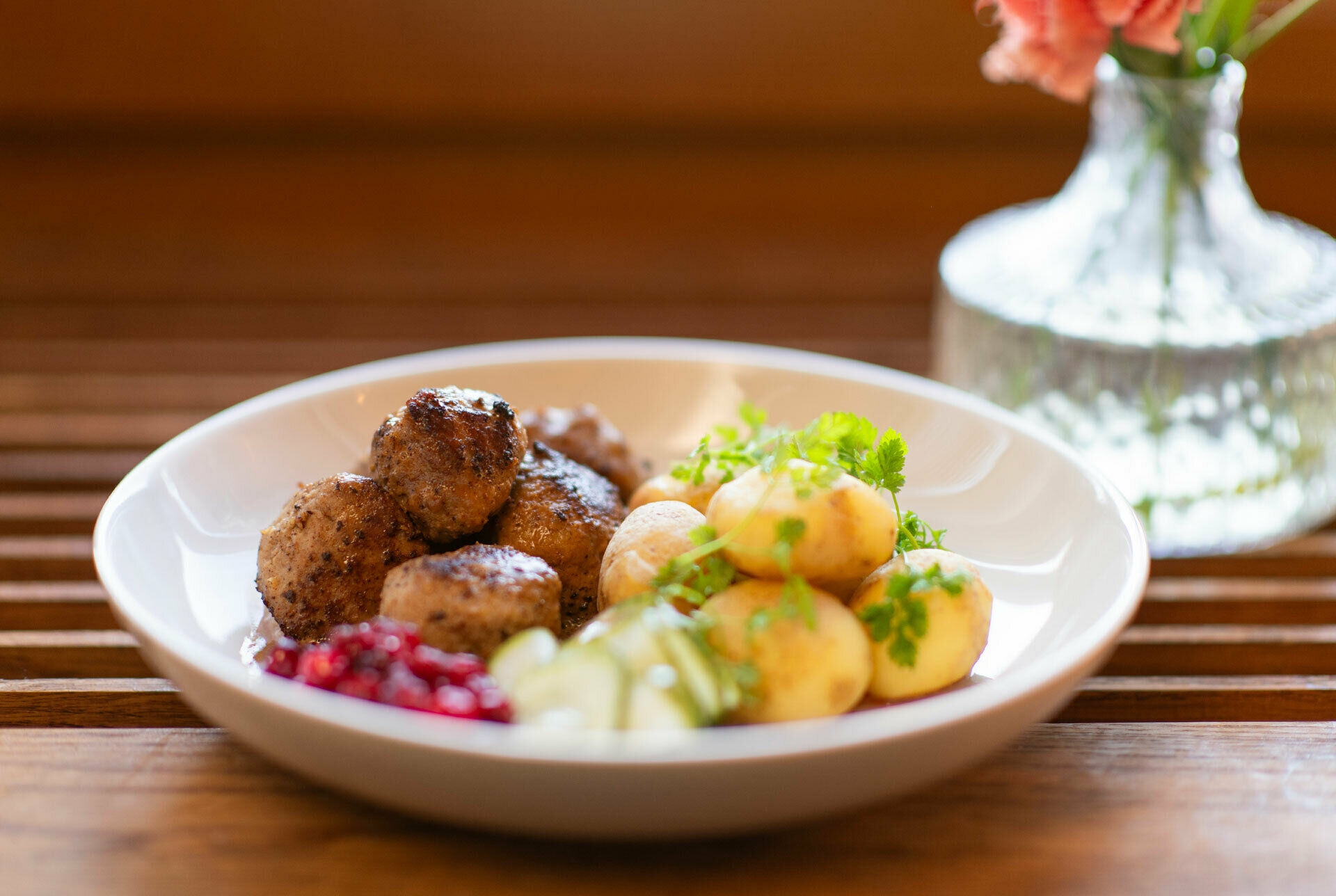 En tallrik med köttbullar, potatis, lingon pressgurka.
