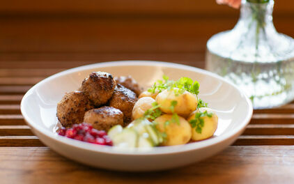 En tallrik med köttbullar, potatis, lingon pressgurka.
