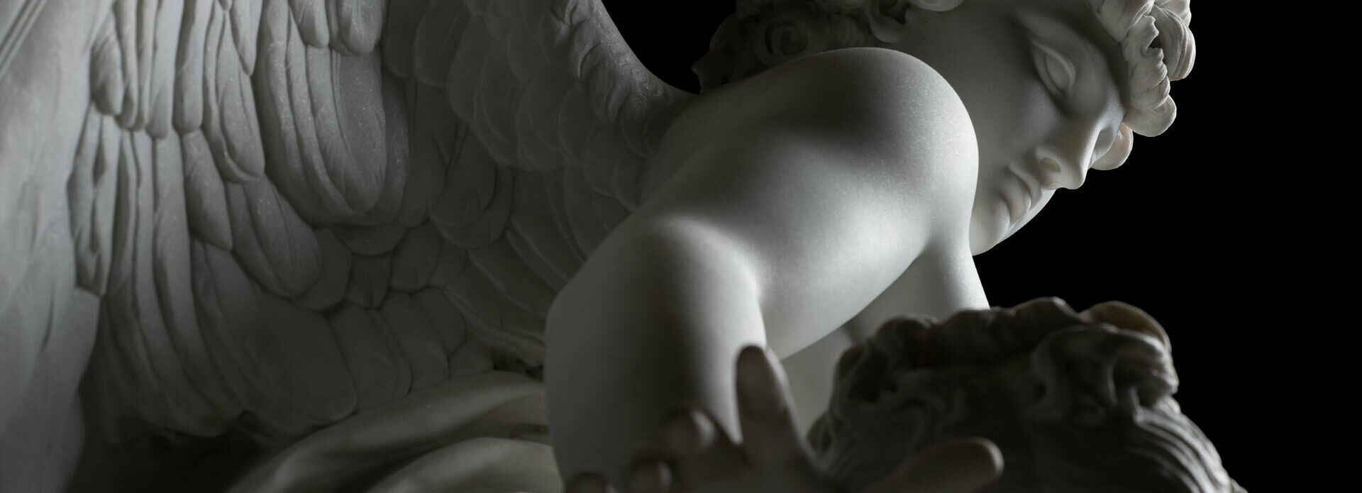 Detalj av marmorskulptur Amor och Psyke. Den bevingade Amor ses snett underifrån.