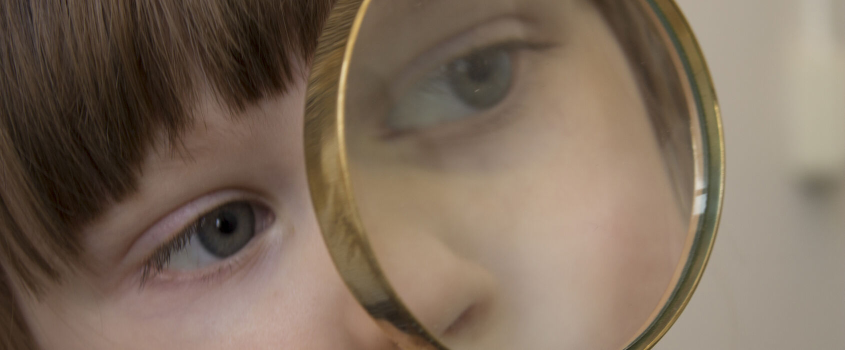 Närbild på ett litet bar som håller, och tittar i, ett förstoringsglas framför sig.