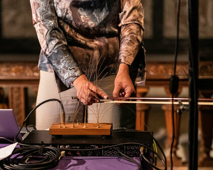 Händerna på en kvinna som står och gör musik på ett elektroniskt instrument.