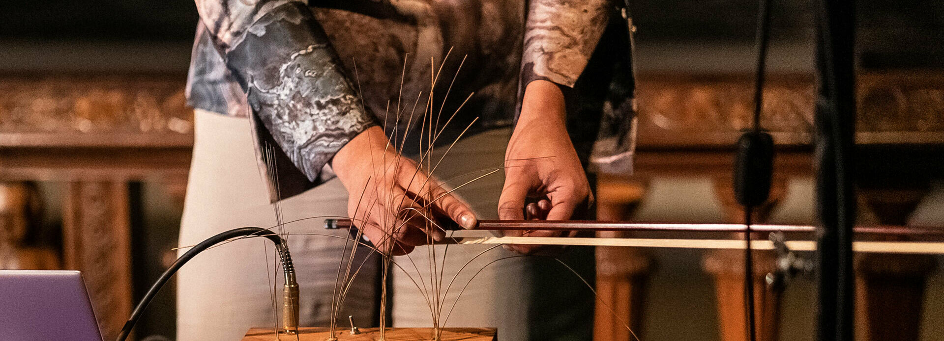 Händerna på en kvinna som står och gör musik på ett elektroniskt instrument.
