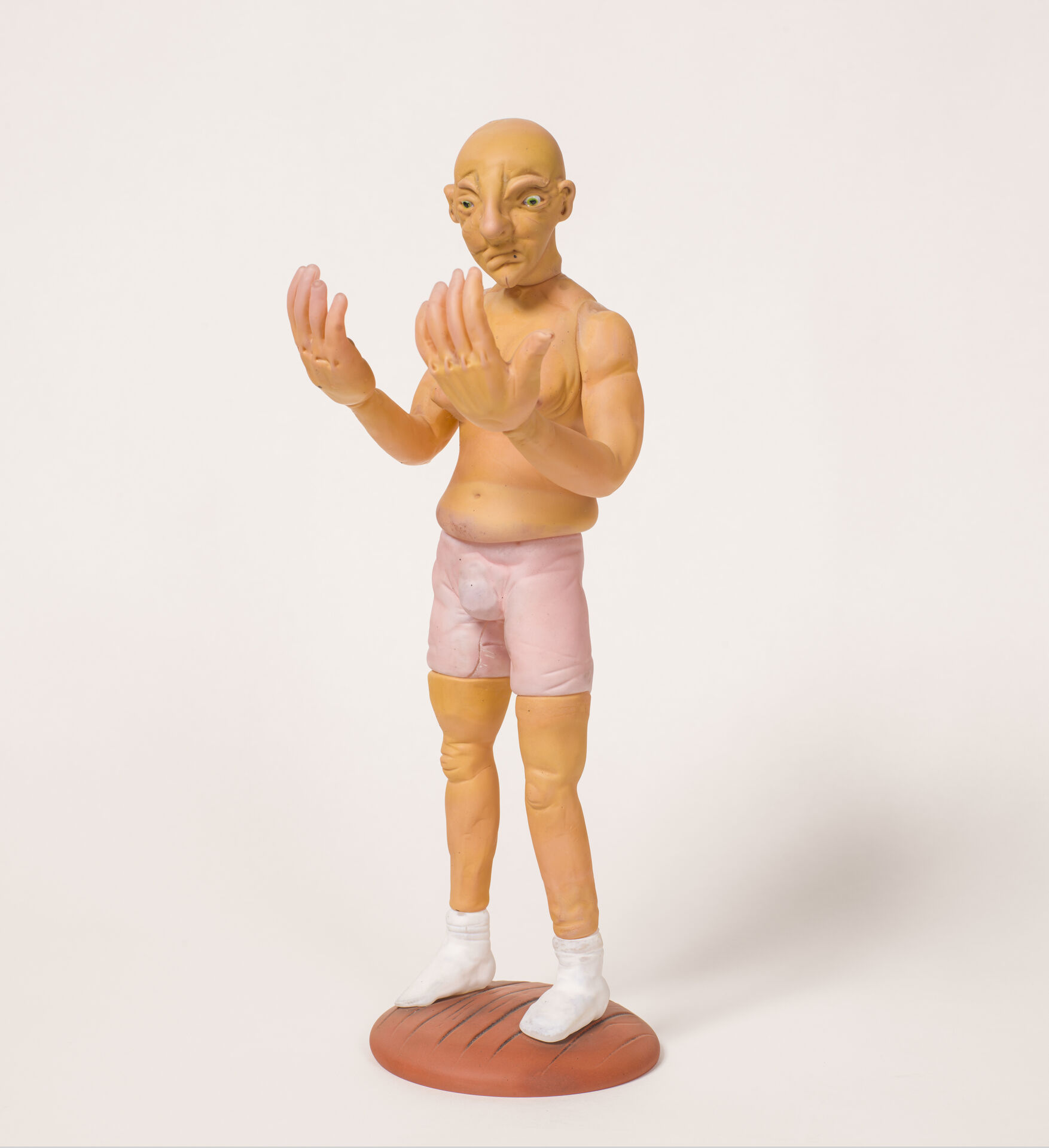 Glasskulptur av man som tittar på sina stora händer. Naken förutom kalsonger och strumpor.