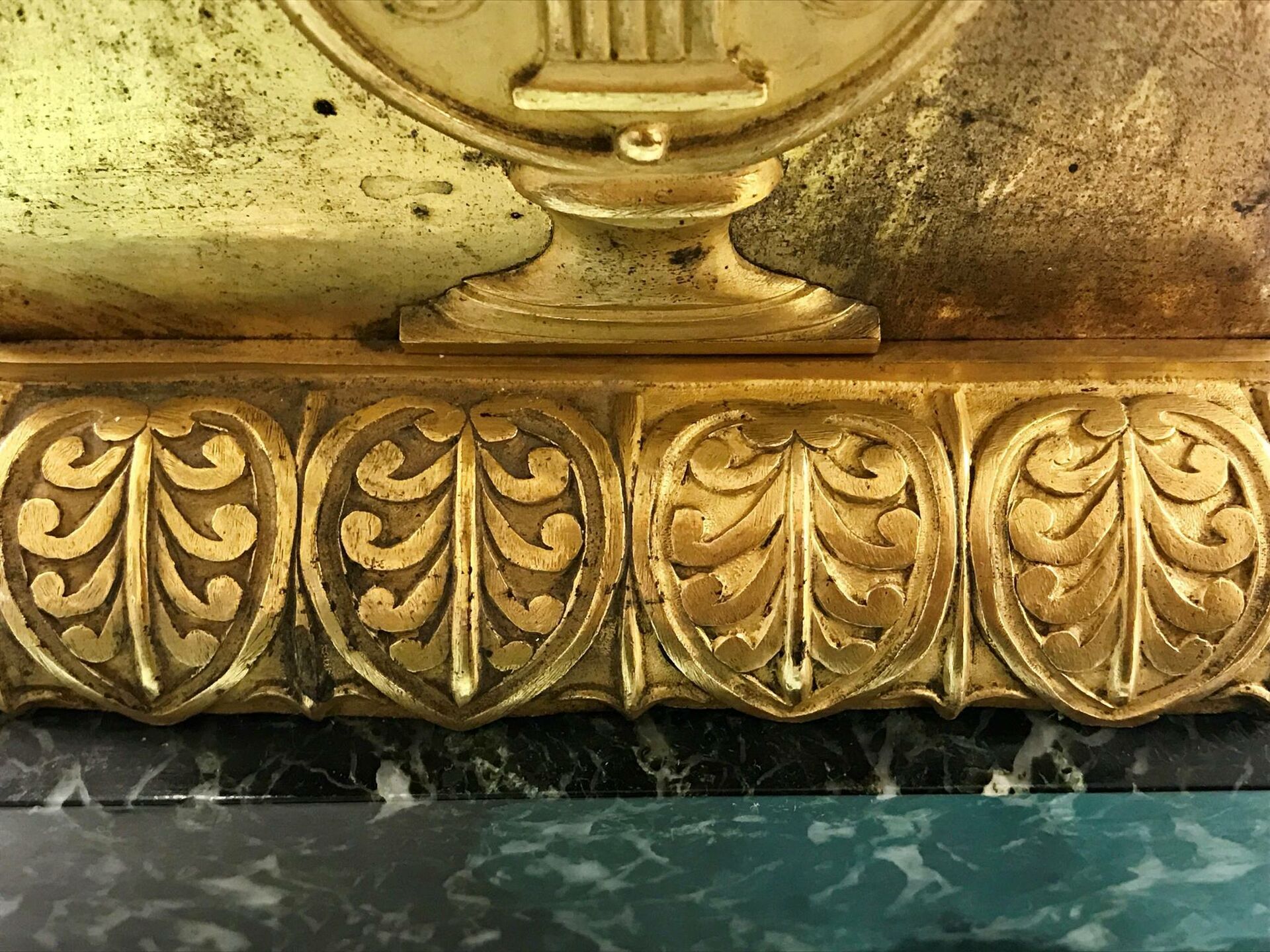 Brännförgylld akantusbård, delvis rengjord, på sockeln till ett bordsur i museets samlingar