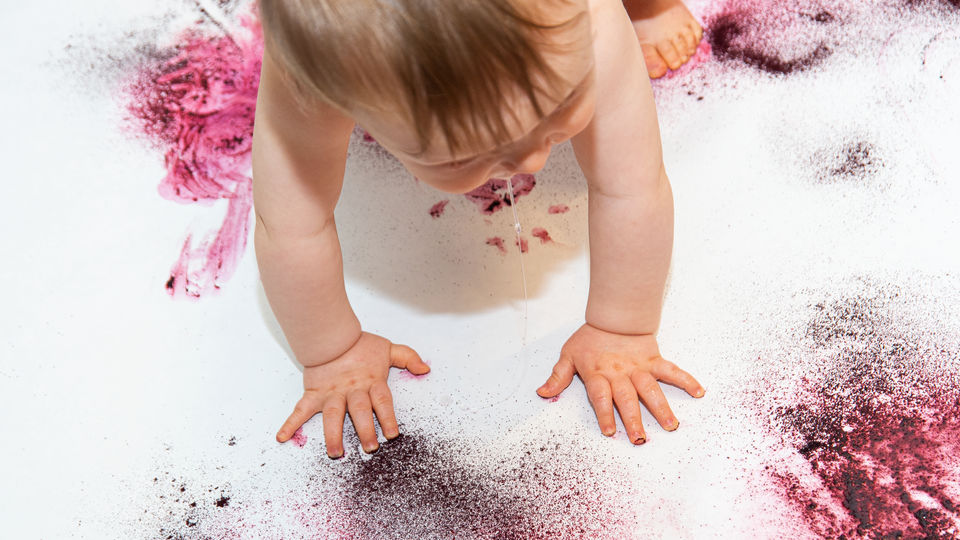Baby krypande på vitt underlag med färgstänk