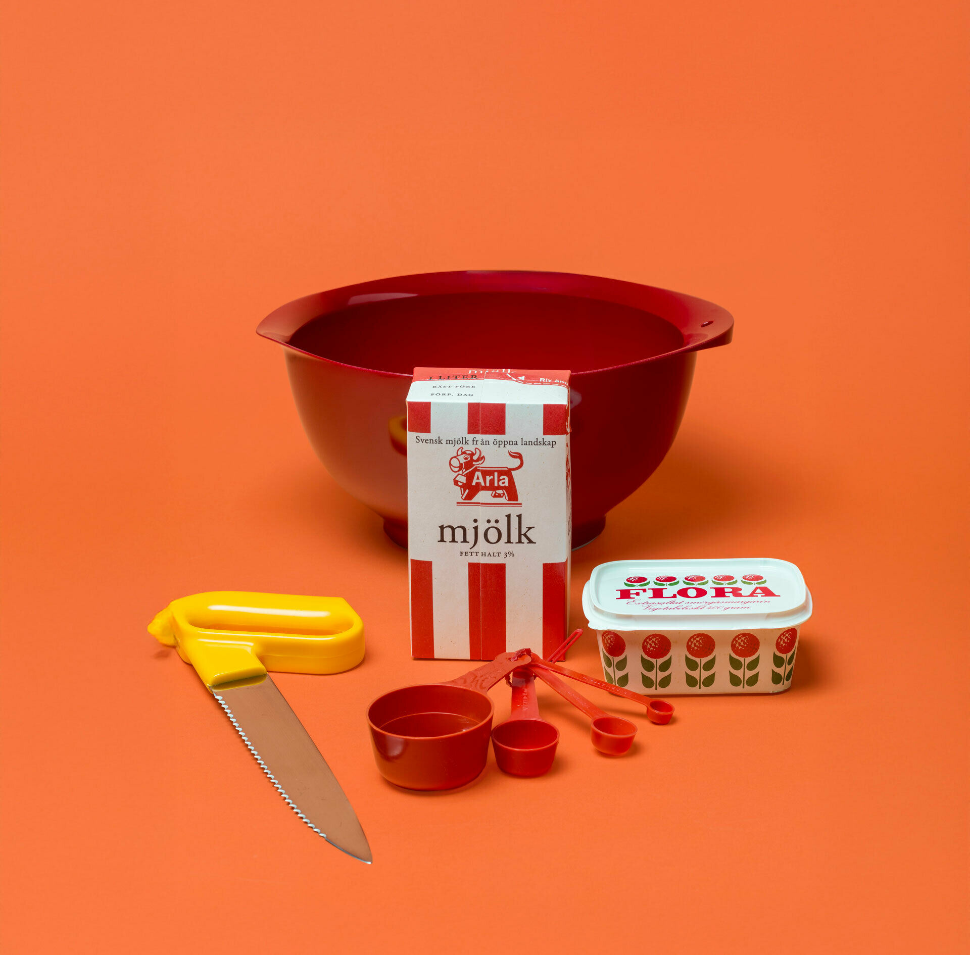 En plastsskål, en brödsåg, en margarinask, en måttsats, en förpackning för mjölk.