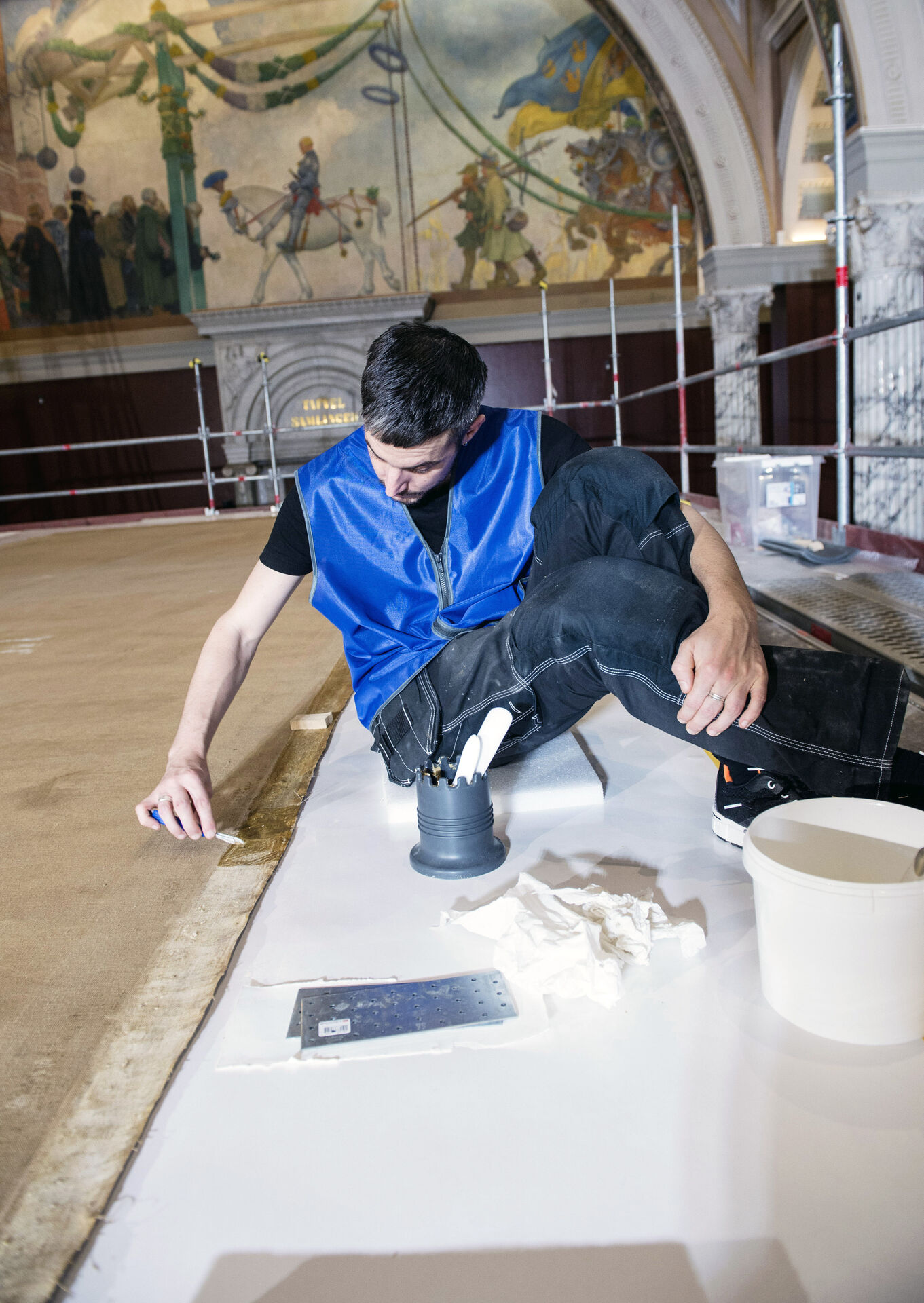 Konservator penslar lim på målningens kanter.