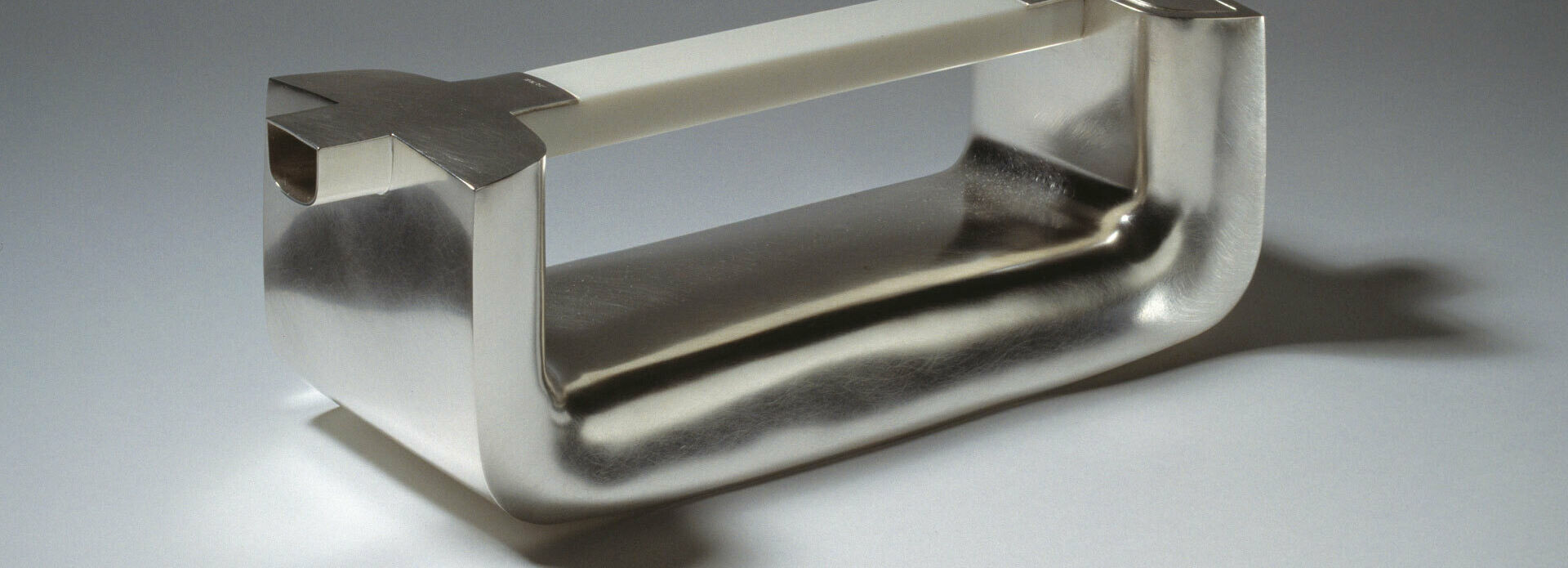 Kanna i silver i form av ett handtag.