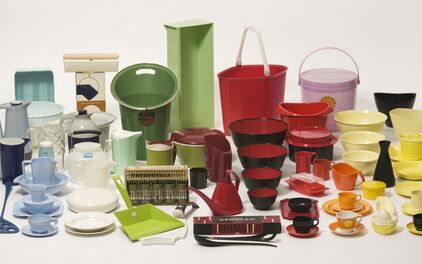 En samling färgglada plastföremål för hushållet – inklusive skålar, kannor, koppar, fat, brickor och vattenkannor – arrangerade tätt tillsammans på vit bakgrund. Föremålen är i retrostil och visar exempel på svensk plastdesign från 1900-talet.