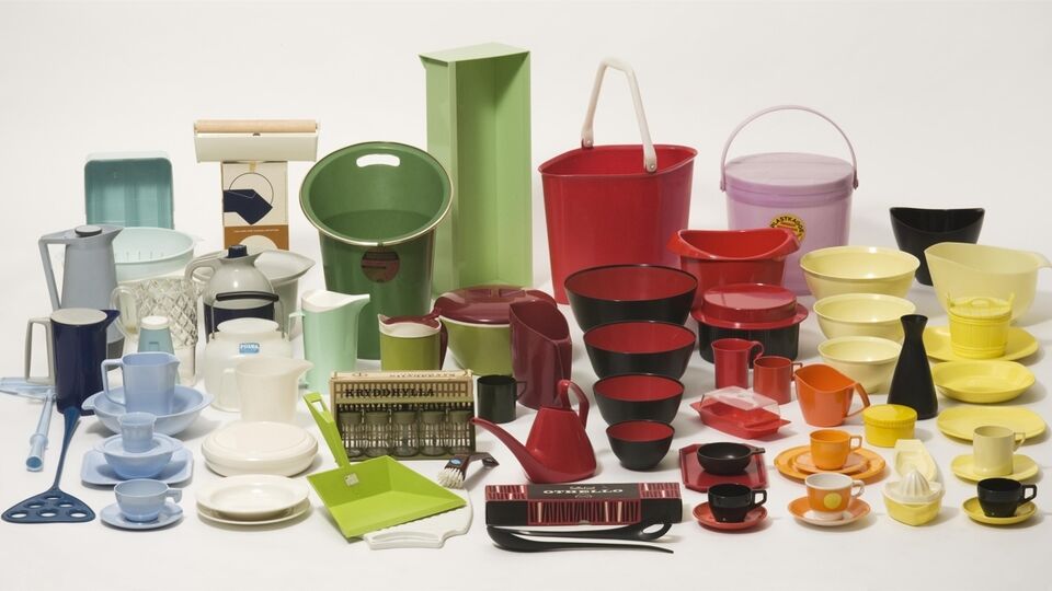 En samling färgglada plastföremål för hushållet – inklusive skålar, kannor, koppar, fat, brickor och vattenkannor – arrangerade tätt tillsammans på vit bakgrund. Föremålen är i retrostil och visar exempel på svensk plastdesign från 1900-talet.