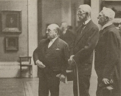 Äldre fotografi föreställande några män, bland andra kung Gustav V, som tittar på målningar som hänger på en museivägg.