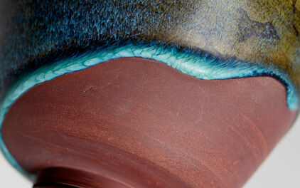 Detalj av en keramikskål där glasyr delvis täcker ytan.