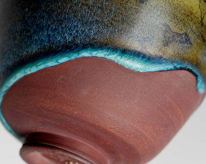 Detalj av en keramikskål där glasyr delvis täcker ytan.