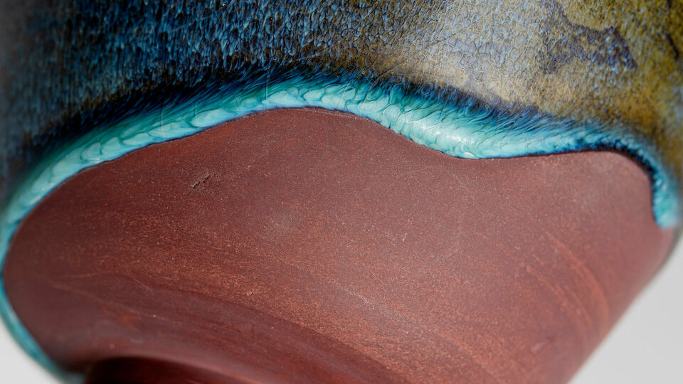 Detalj av en keramikskål där glasyr delvis täcker ytan.