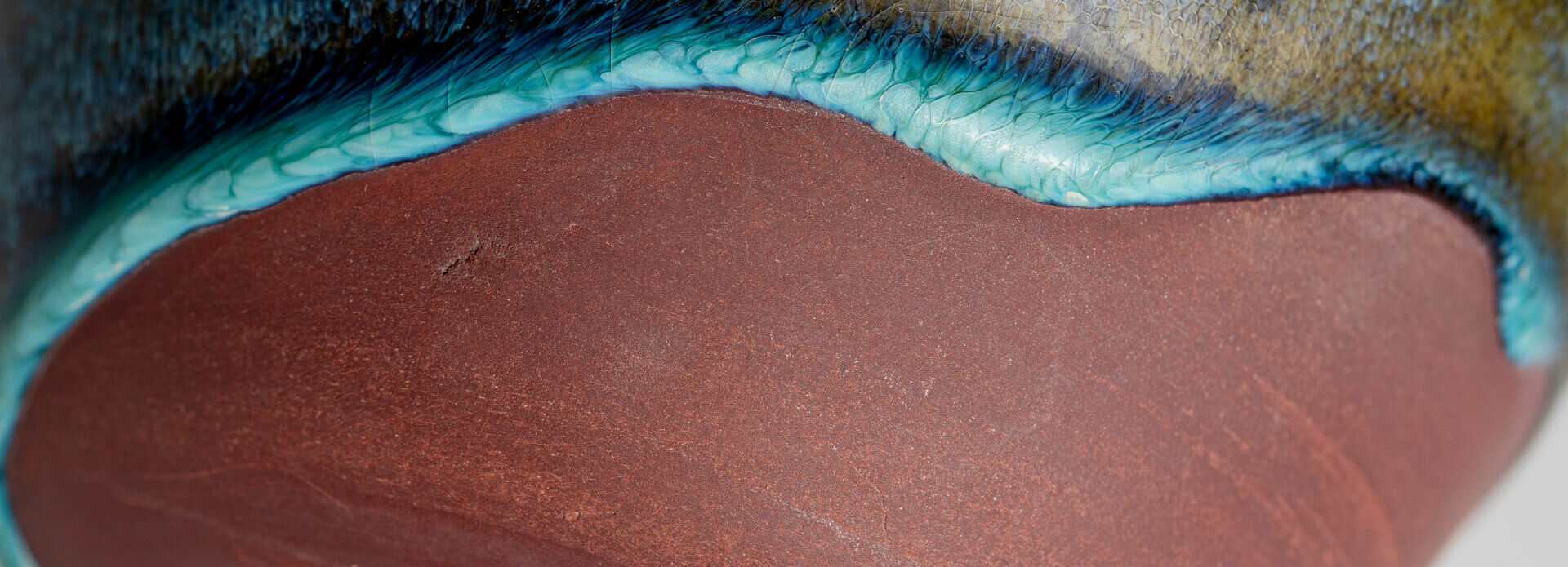 Detalj av en keramikskål där glasyr delvis täcker ytan.