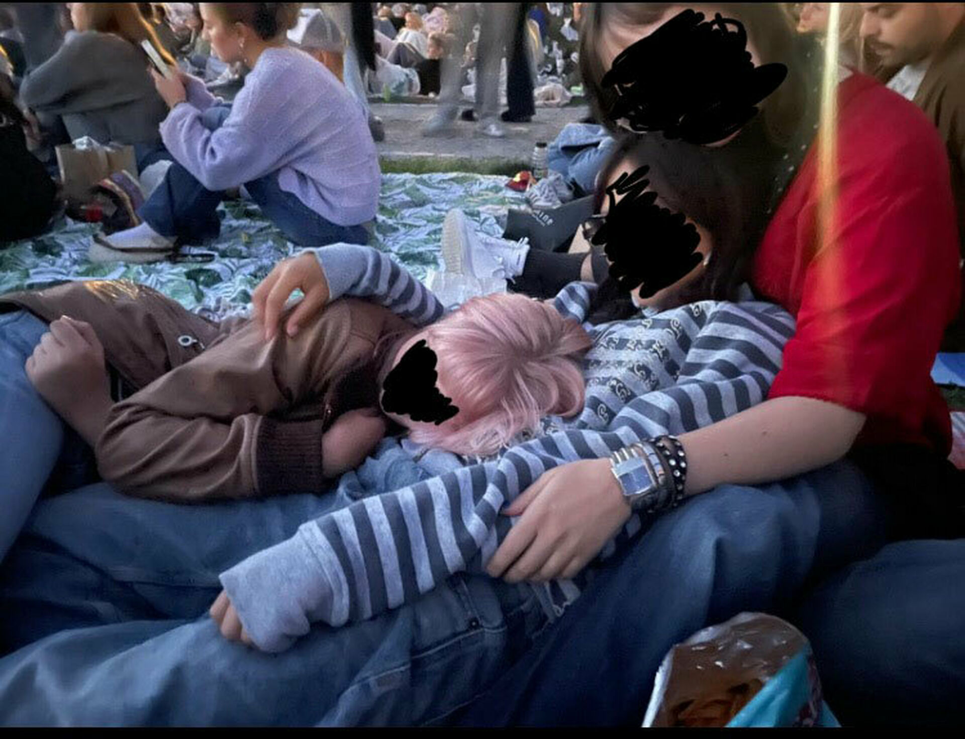 Några unga människor, med överkluddade ansikten, sitter och ligger i något som tycks vara en festivalmiljö.