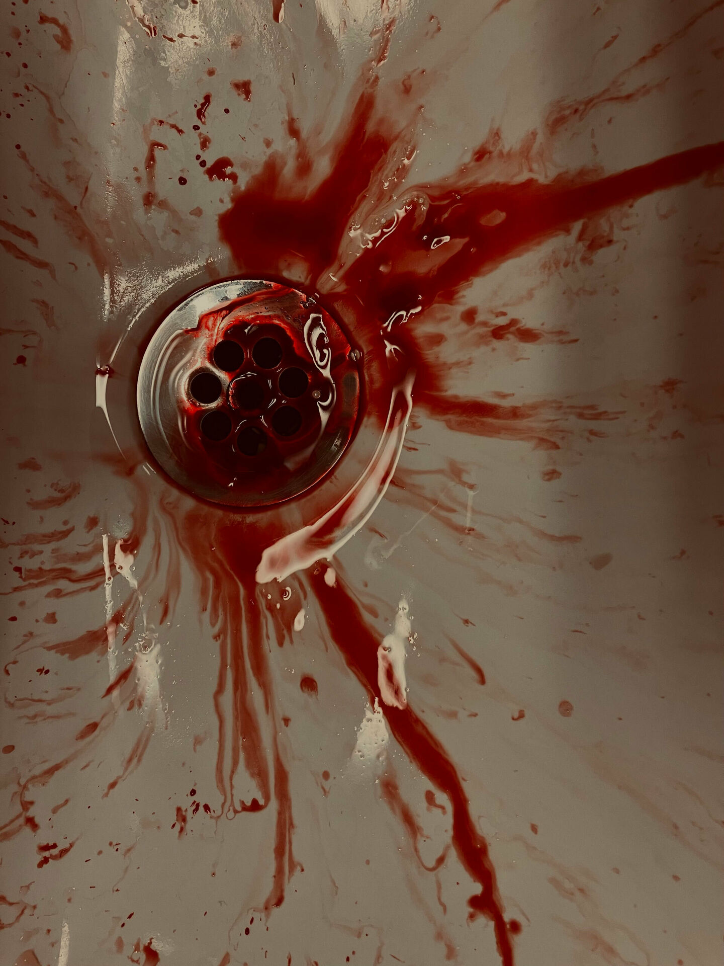 Blod som rinner ner i avloppet i ett handfat.