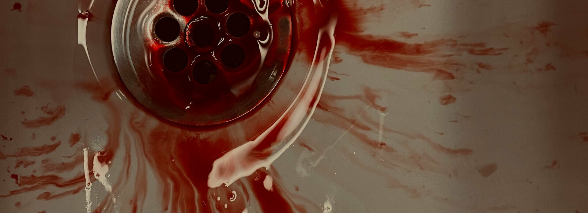 Blod som rinner ner i avloppet i ett handfat.