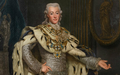 Äldre porträtt föreställlande kung Gustav III. Han bär en silverbroderad dräkt och över den en mantel i hermelinpäls.