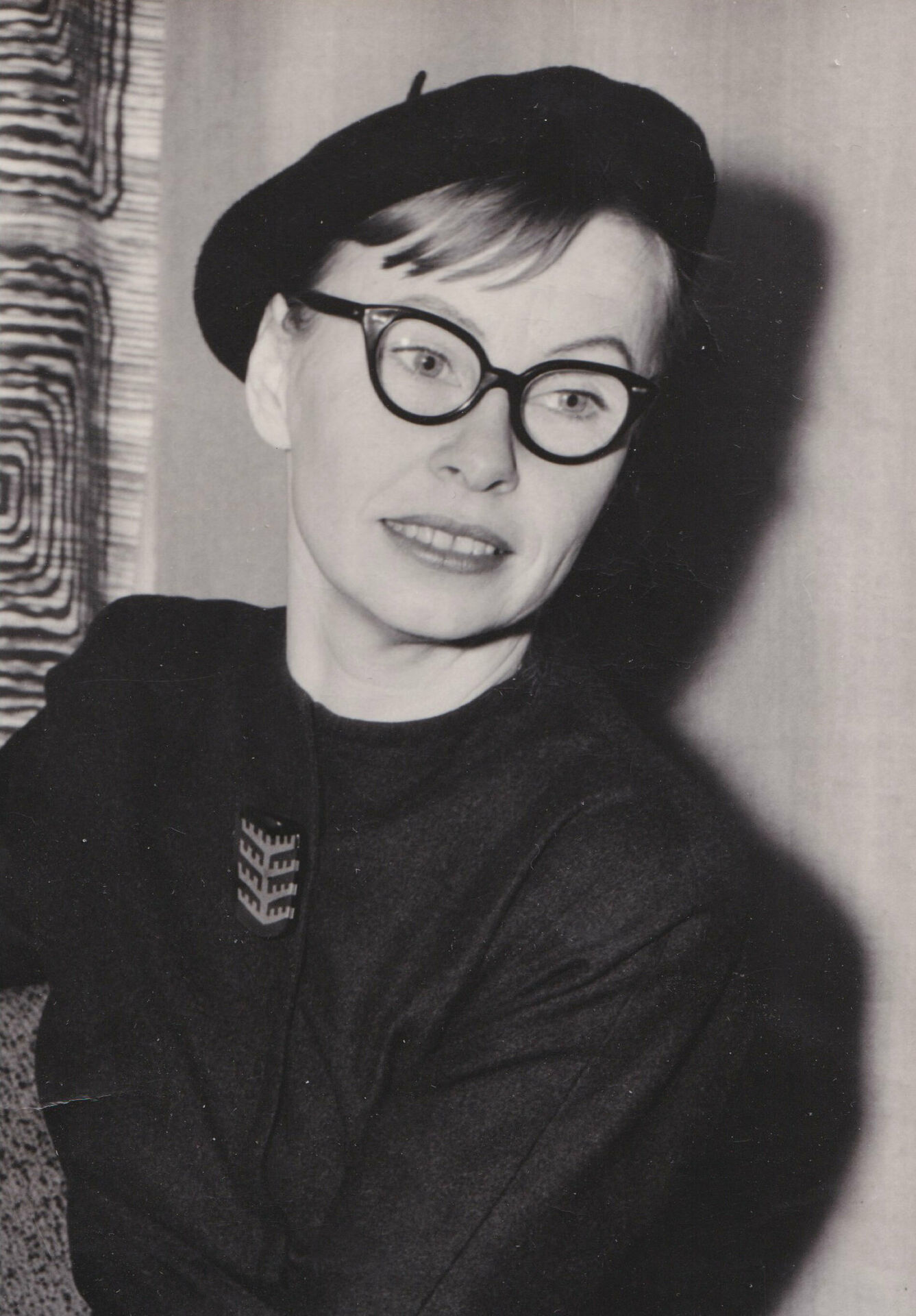 Svartvitt porträttfotografi av en kvinna i mörk klänning och basker.