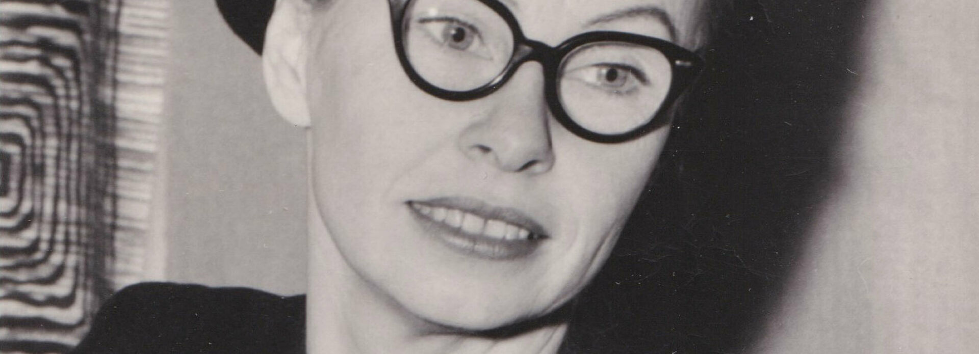 Svartvitt porträttfotografi av en kvinna i mörk klänning och basker.