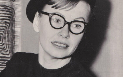 Svartvitt porträttfotografi av en kvinna i mörk klänning och basker.