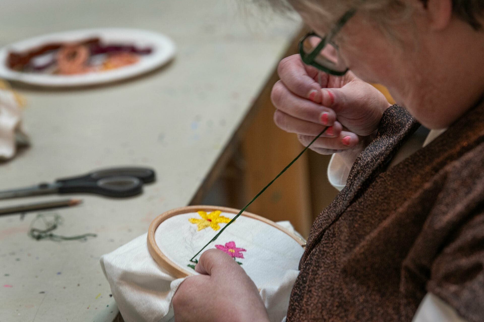 En kvinna som broderar blommor på ett tyg.
