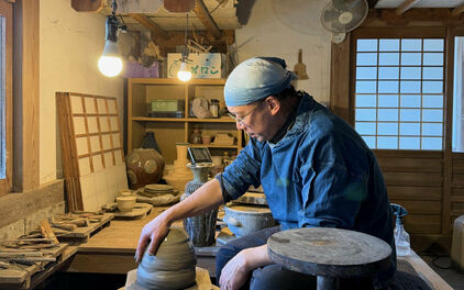 en man som sitter på huk och drejar i en keramikverkstad.