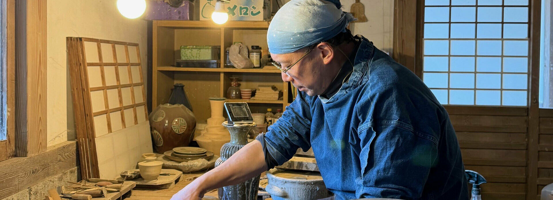 en man som sitter på huk och drejar i en keramikverkstad.