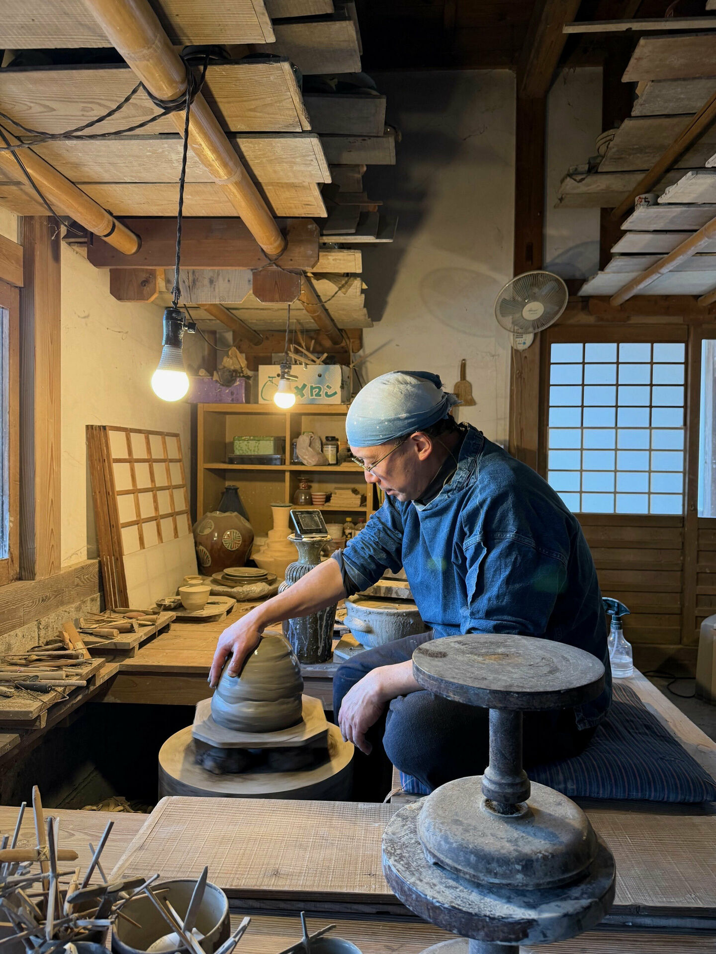 en man som sitter på huk och drejar i en keramikverkstad.