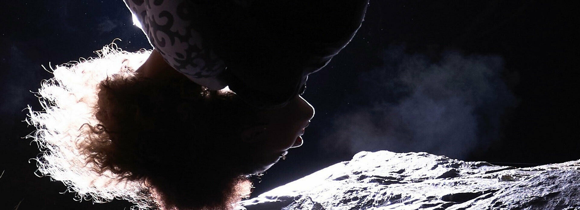 En person som tycks hänga upp och ner, med månlandskap bakom sig.