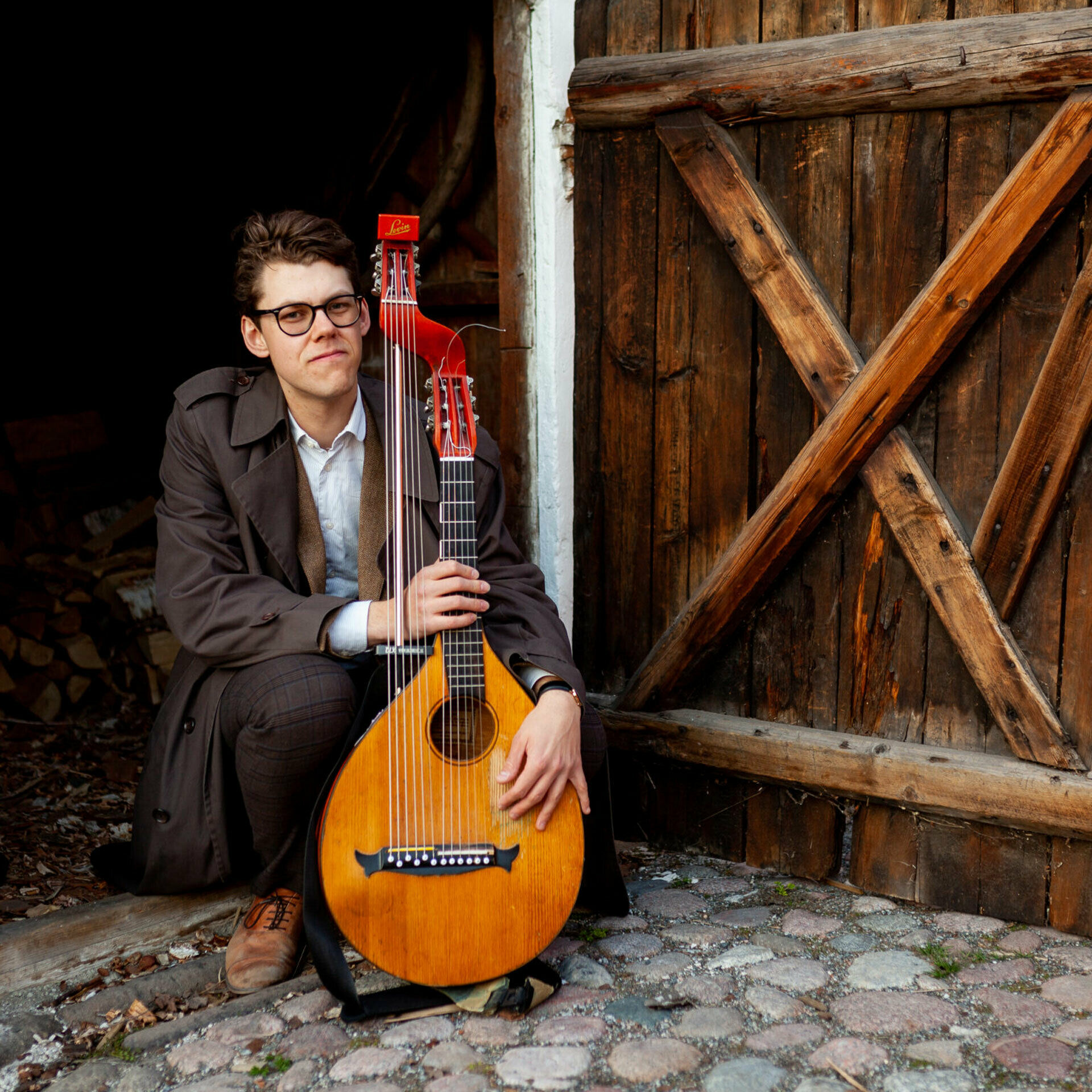 Man som sitter på huk och håller i en luta.