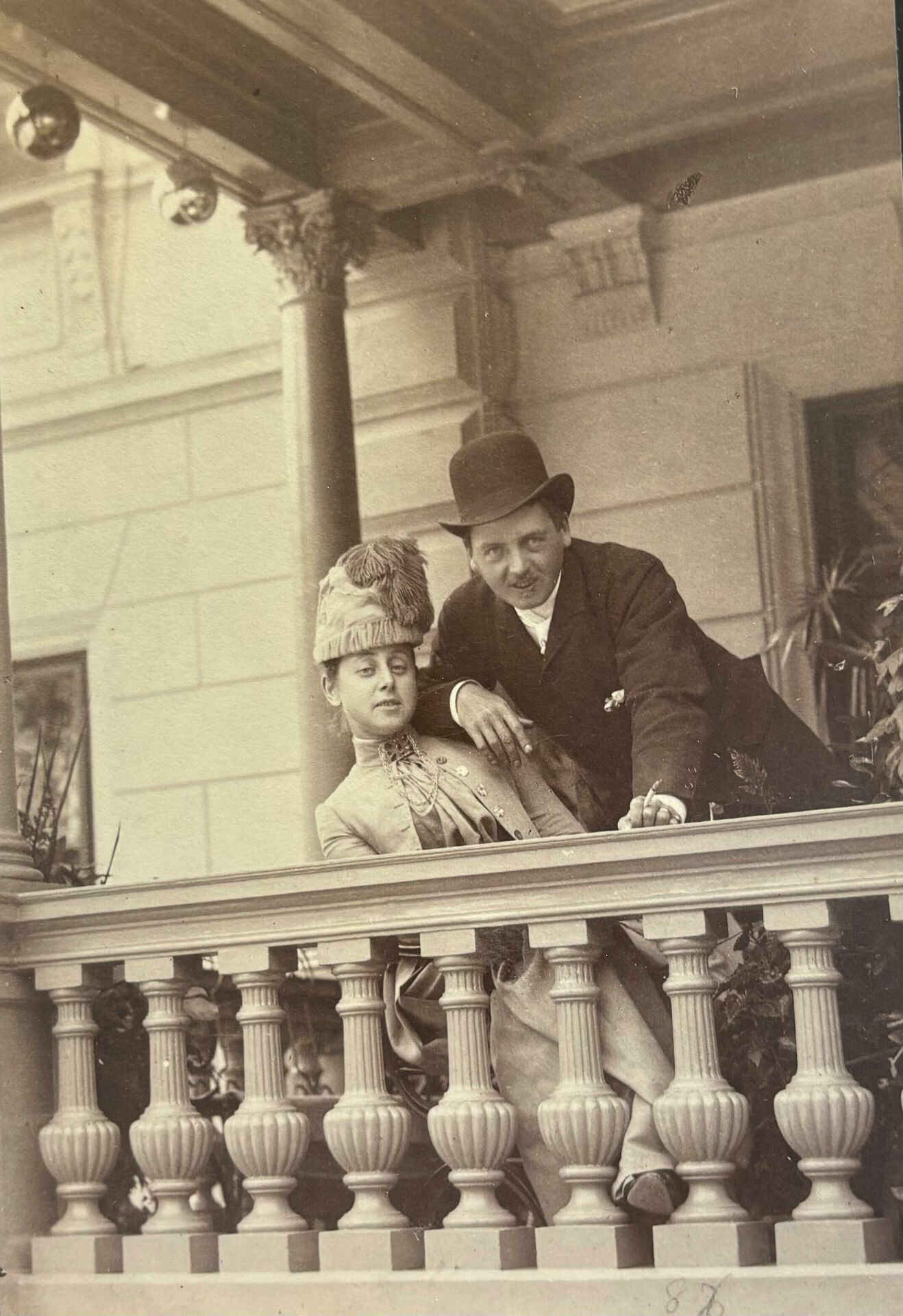 Äldre fotografi av en man och en kvinna som står och lutar sig mot en balustrad på en balkong eller terrass.