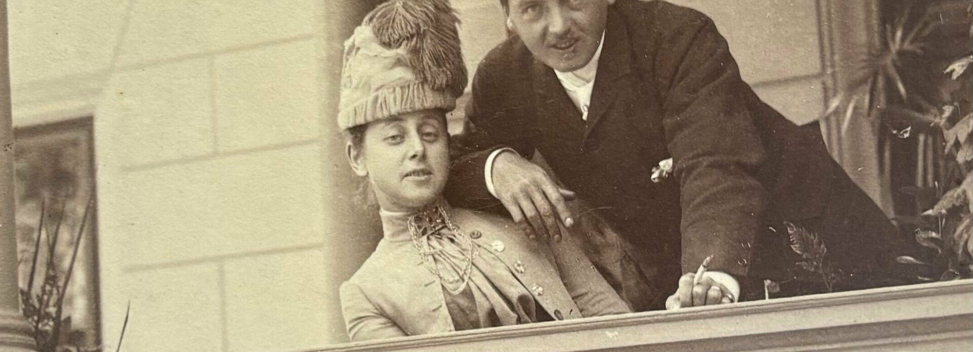 Äldre fotografi av en man och en kvinna som står och lutar sig mot en balustrad på en balkong eller terrass.