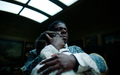 Foto från film, med en man i 1700-talskläder som står och håller om en annan man.