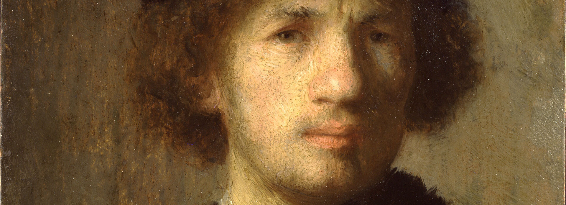 Porträtt av en ung man i brun jacka och mössa.